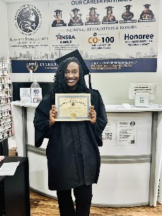 Louisville Beauty Academy 2026 graduate with certificate in front of the national recognition and honors wall