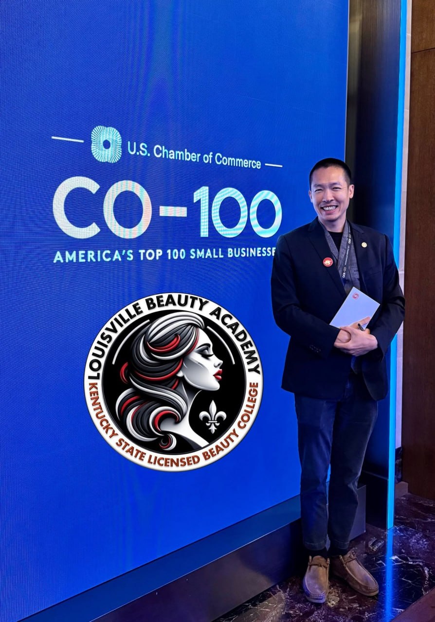 Di Tran standing beside a U.S. Chamber CO-100 display with the Louisville Beauty Academy logo